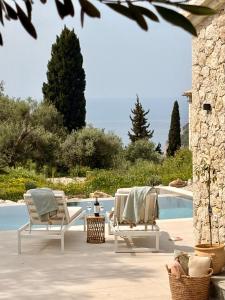 a patio with two chairs and a table and a pool at Villa Xalupi - Design-Villa mit Pool und Meerblick in Paleokastritsa