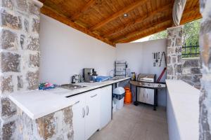 a kitchen with white counters and a stone wall at Casa Bellavista in Tivat +32 photos