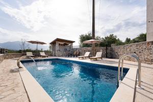 a swimming pool with chairs and umbrellas on a house at Casa Bellavista in Tivat