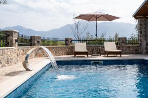 a pool with an umbrella and two chairs and a table at Casa Bellavista in Tivat