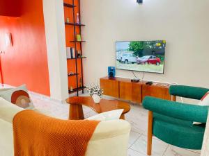 a living room with a tv and two chairs at Rieti Yamehome in Yaoundé