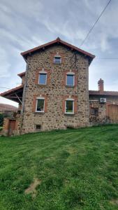 a large stone house with a grass field in front of it at Gerlande 2 in Bourg-Argental