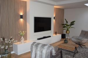 a living room with a television on a white wall at De Witte Gans in Ootmarsum