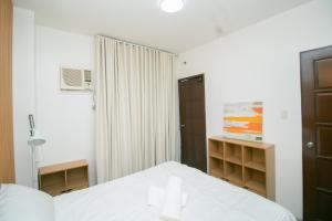 a bedroom with a white bed and a closet at 206 Executive Granvia Suites in Cagayan de Oro