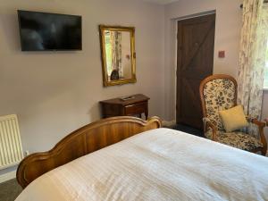 a bedroom with a bed and a mirror and a chair at Primrose Cottage Westhead in Westhead