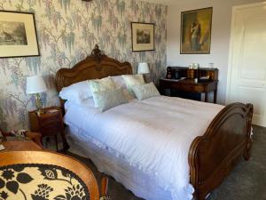 a bedroom with a large bed with white sheets at Primrose Cottage Westhead in Westhead