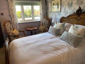 a bedroom with a bed with two chairs and a window at Primrose Cottage Westhead in Westhead
