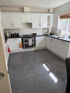 a kitchen with white cabinets and a tile floor at Cosy House in Reading