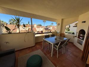 a dining room with a table and chairs and large windows at La Manga Club, Las Palmeras 12 in La Manga del Mar Menor