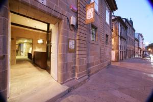 un bâtiment en briques avec une porte ouverte dans une rue dans l'établissement Hotel A Tafona do Peregrino, à Saint-Jacques-de-Compostelle