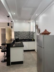 a large kitchen with white cabinets and a refrigerator at Tiwaline Tarsime App E in Sidi Ifni