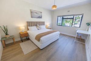 a bedroom with a white bed and a window at Modern Seaside Apartment in Fish Hoek
