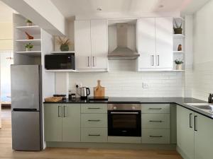 a kitchen with white cabinets and a stainless steel refrigerator at Modern Seaside Apartment in Fish Hoek