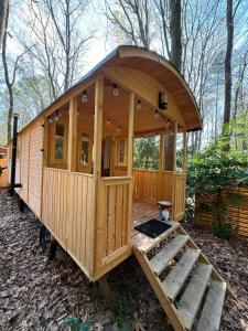 a wooden cabin with a porch in the woods at Pipowagen aan het Wandelpad in Lanaken +2 photos