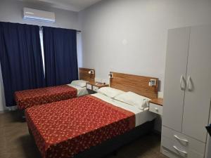 two beds in a hotel room with blue curtains at Hotel KEY´S in Buenos Aires