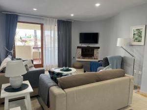 a living room with a couch and chairs and a tv at La Manga Club, Las Palmeras 12 in La Manga del Mar Menor