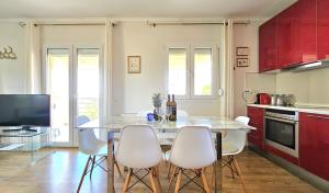 a kitchen with a table with white chairs and red cabinets at Alivia Garden in Paliouri