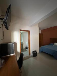 ein Schlafzimmer mit Bett, Fernseher und Spiegel in der Unterkunft Hotel Sol del Pacifico in Lázaro Cárdenas
