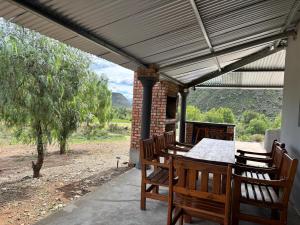 a patio with a table and chairs under awning at Gamtoosberg Cottage in Oudtshoorn