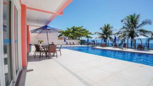a swimming pool with tables and chairs next to a building at Pousada Vila do Coral in Bombinhas