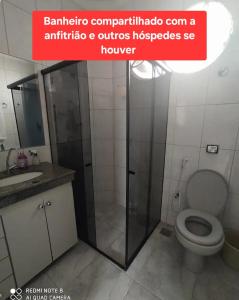 a bathroom with a toilet and a glass shower at Quarto privado com ar condicionado in Governador Valadares