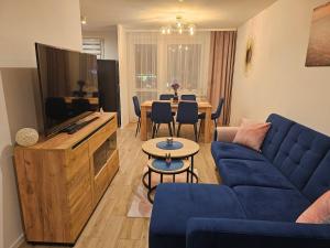 a living room with a blue couch and a tv at Szybowcowa View Apartment in Jelenia Góra