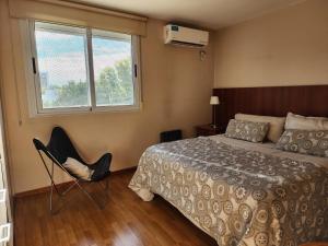 a bedroom with a bed and a chair and a window at Piero House in Villa Mercedes