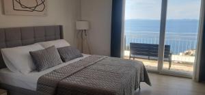 a bedroom with a bed with a view of the ocean at Apartmani Vesna Miliša in Primošten