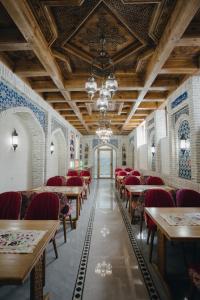 an empty dining room with tables and red chairs at Imranbek Boutique Hotel in Bukhara