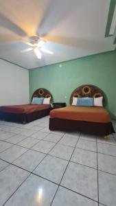two beds in a room with green walls at Hotel Meson Mariano Matamoros in Querétaro