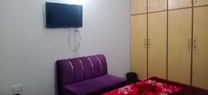 a purple chair in a room with a tv at Eden Plus Executive Hotel Lahore in Lahore +56 photos