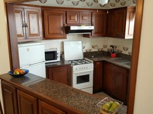 a kitchen with wooden cabinets and a white stove top oven at Sol y Playa in Puerto Naos