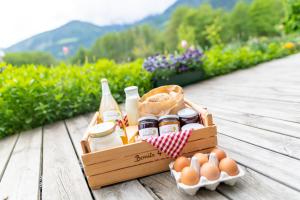 Eine Kiste mit Lebensmitteln und Eiern auf einem Holztisch in der Unterkunft HAUSERGUT Ruhige Bio-Bauernhof Ferienwohnungen im Vinschgau mit Ortlerblick in Schluderns