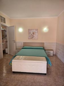 a bedroom with a bed with a green comforter at La Rosa dei Venti B&B in Chia
