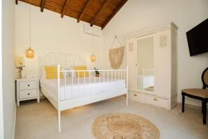 a white bedroom with a bed and a chair at Petit Palace in Lefkimmi