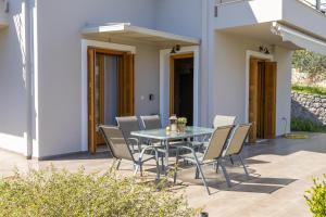 a glass table and chairs on a patio at Aricobé in Ancient Epidauros