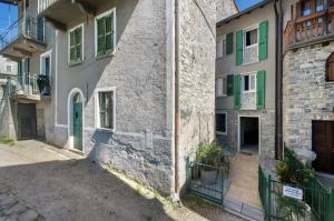 a building with green shuttered windows and a courtyard at Prima Del Cielo - Appartamento Lago in Esino Lario