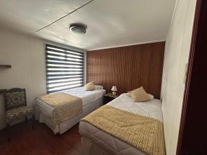 ein Hotelzimmer mit zwei Betten und einem Fenster in der Unterkunft Hotel Milodon in Puerto Natales