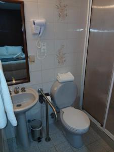 ein Badezimmer mit Toilette, Waschbecken und Dusche in der Unterkunft Hotel Milodon in Puerto Natales