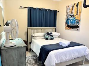 a bedroom with two beds and a blue curtain and a fan at Gamtoosberg Cottage in Oudtshoorn