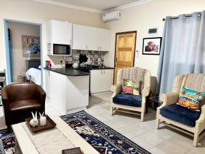 a kitchen and living room with two chairs and a table at Gamtoosberg Cottage in Oudtshoorn +25 photos