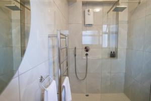 a shower with a glass door in a bathroom at Modern Seaside Apartment in Fish Hoek +4 photos