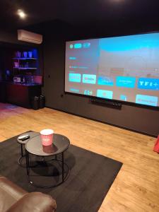 a person sitting in a room with a table in front of a screen at Appartement thème cinéma in Cazouls-lès-Béziers