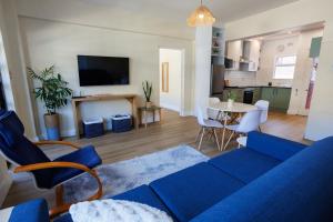 a living room with a blue couch and a table at Modern Seaside Apartment in Fish Hoek