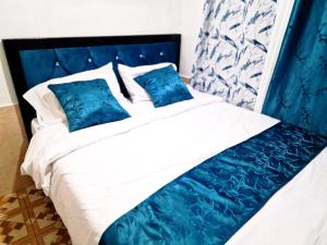 a blue and white bed with white sheets and blue pillows at Cosmic homes Ruiru Kimbo in Ruiru