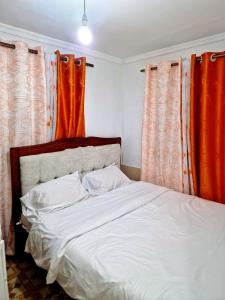 a bedroom with a bed with orange curtains at Cosmic homes Ruiru Kimbo in Ruiru