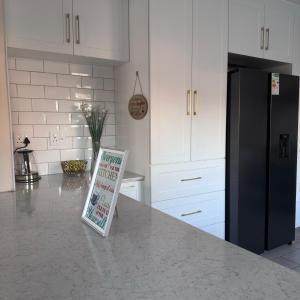 a kitchen with a black refrigerator and a sign on a counter at Terrys place in Malmesbury