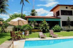 a house with a pool and chairs and an umbrella at Casa Mandacaru Pousada in Cumbuco