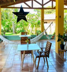 a patio with a hammock and a table and chairs at Casa Mandacaru Pousada in Cumbuco