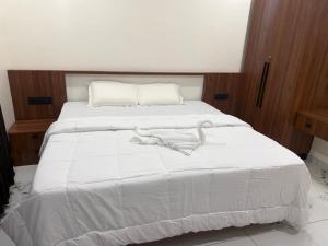 a bedroom with a white bed with wooden walls at Mangro villa in Mayyanād